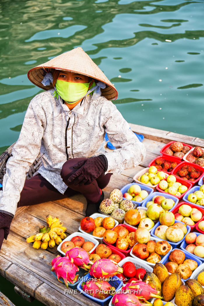 Unidentified woman sells fruits from her boat on Ha Long bay, Vietnam. Floating markets are very popular  as it is only way to move around.