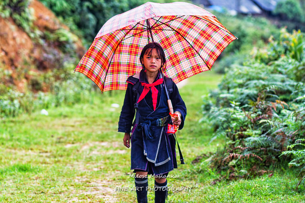 An unidentified girl comes back home from school during a rainy weather in Sapa, Vietnam on 28 September, 2013.  In Vietnam, uniforms are compulsory for all students.