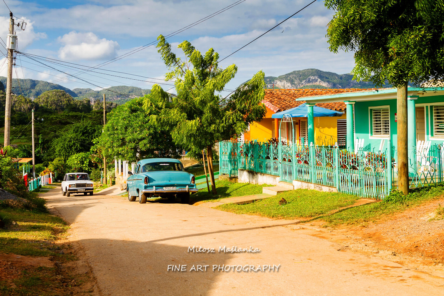 Old fashioned vintage car on a rural road by the summer colorful house in the town of Vinales, Cuba