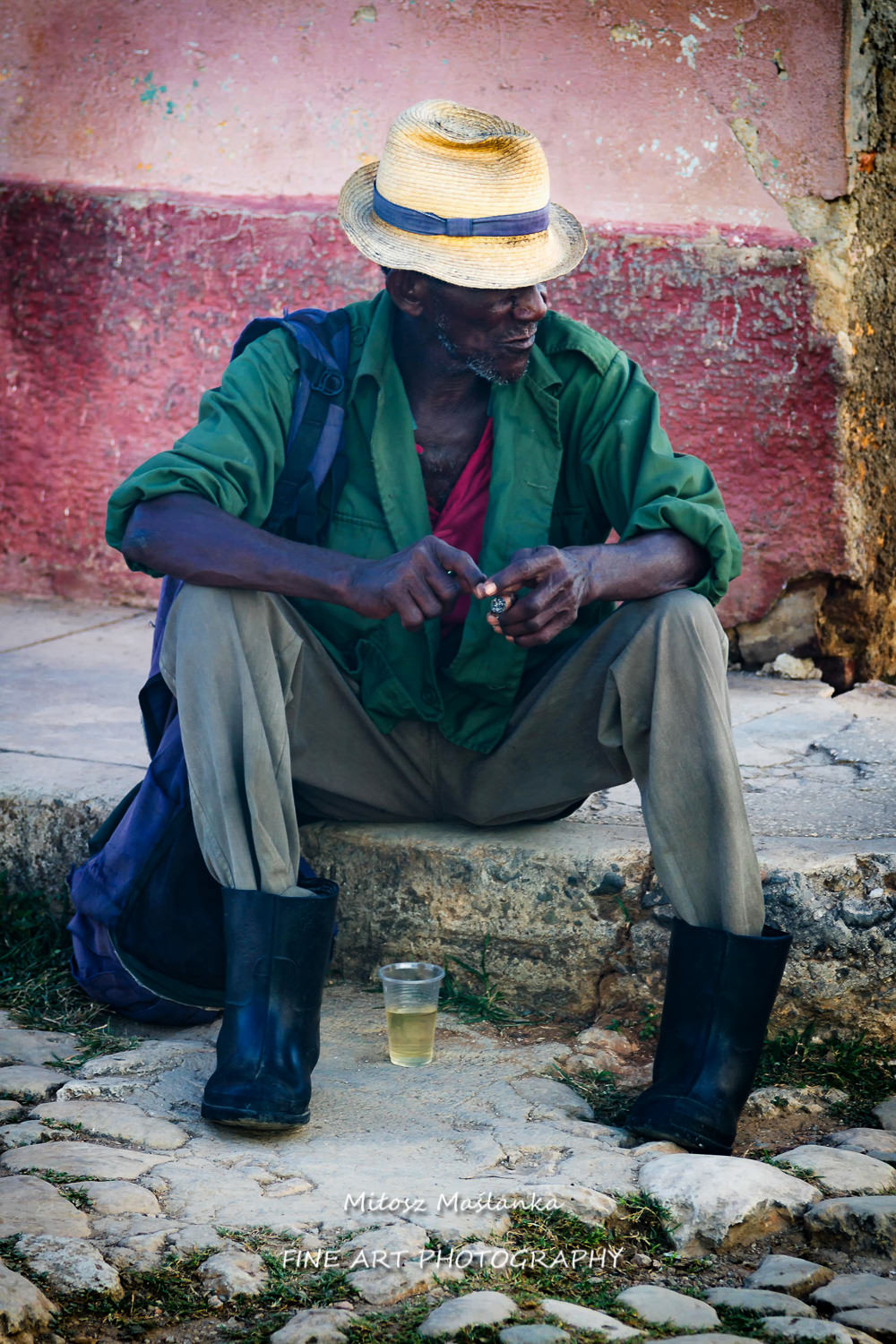 A street portrait of an old cuban man, african carnation, who is sitting in relaxation and smoking his cigarette, calm, no hurry, in a philosophical mood