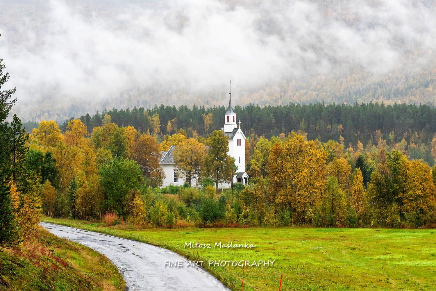 Lonely white church hidden among colorful trees